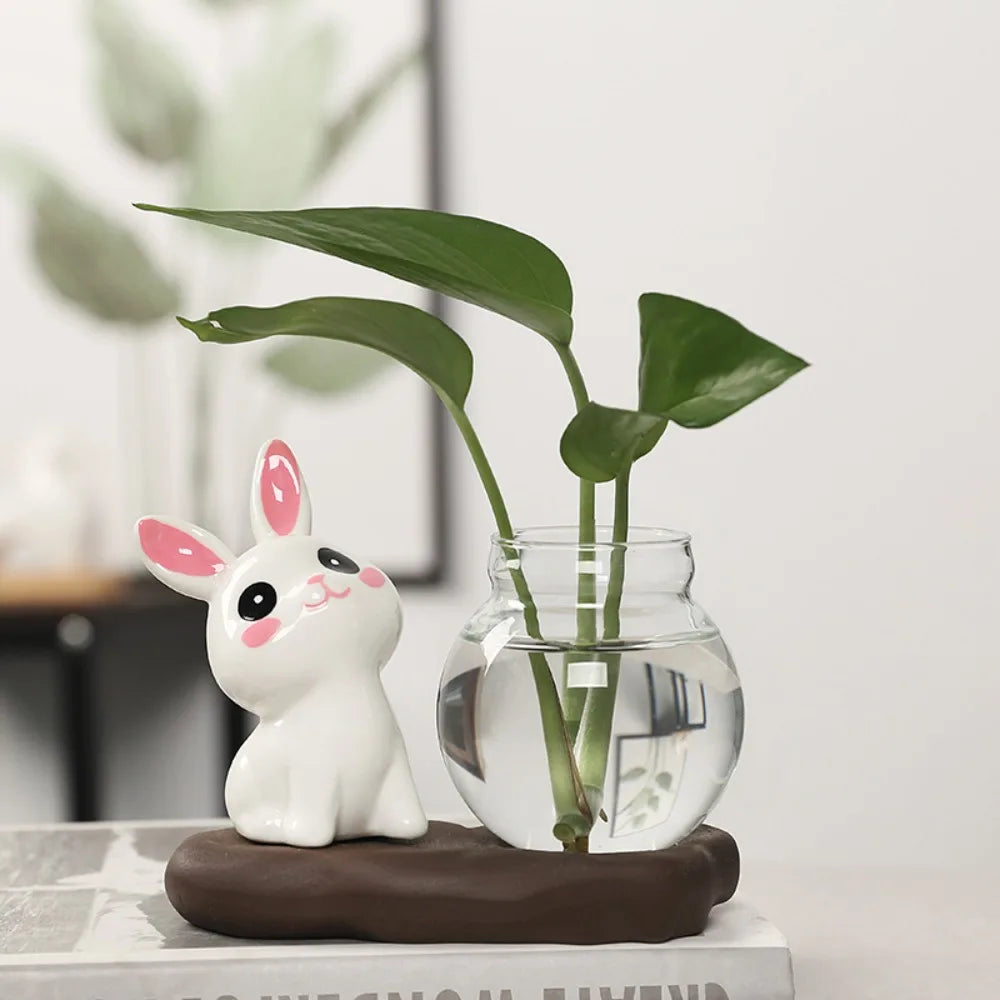 Bunny Glass Bud Vase: 09 sitting white bunny with pink ears beside green cuttings in