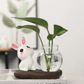 Bunny Glass Bud Vase: 09 sitting white bunny with pink ears beside green cuttings in