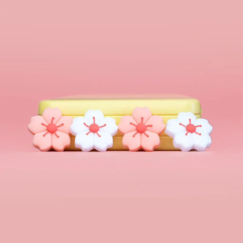 Sakura Flower Switch Thumb Grip Caps: Four sakura flower thumb caps lined up on a yellow stand