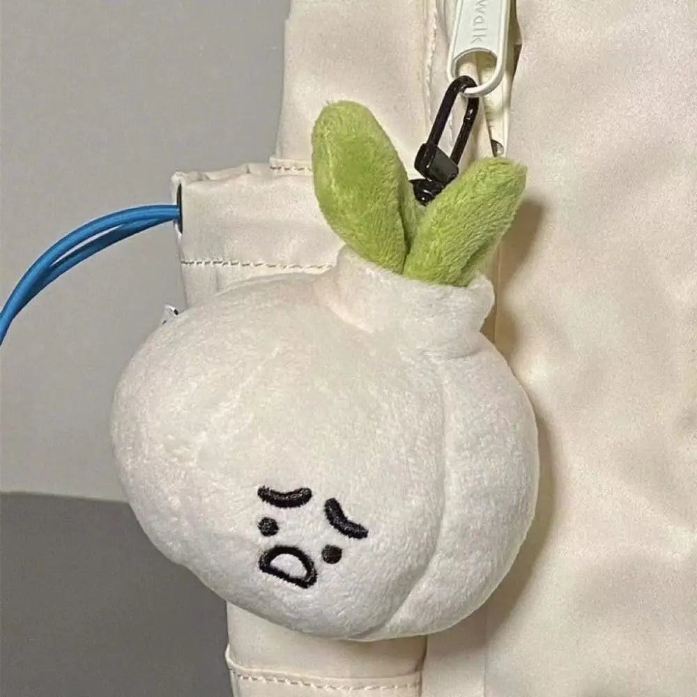 Grumpy Garlic Plush Keychain: Garlic plush charm hanging on a beige bag 01