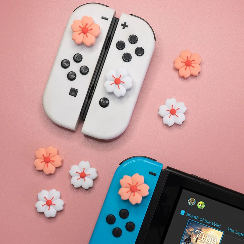 Sakura Flower Switch Thumb Grip Caps: Pink and white sakura thumb grips displayed with white and blue controllers