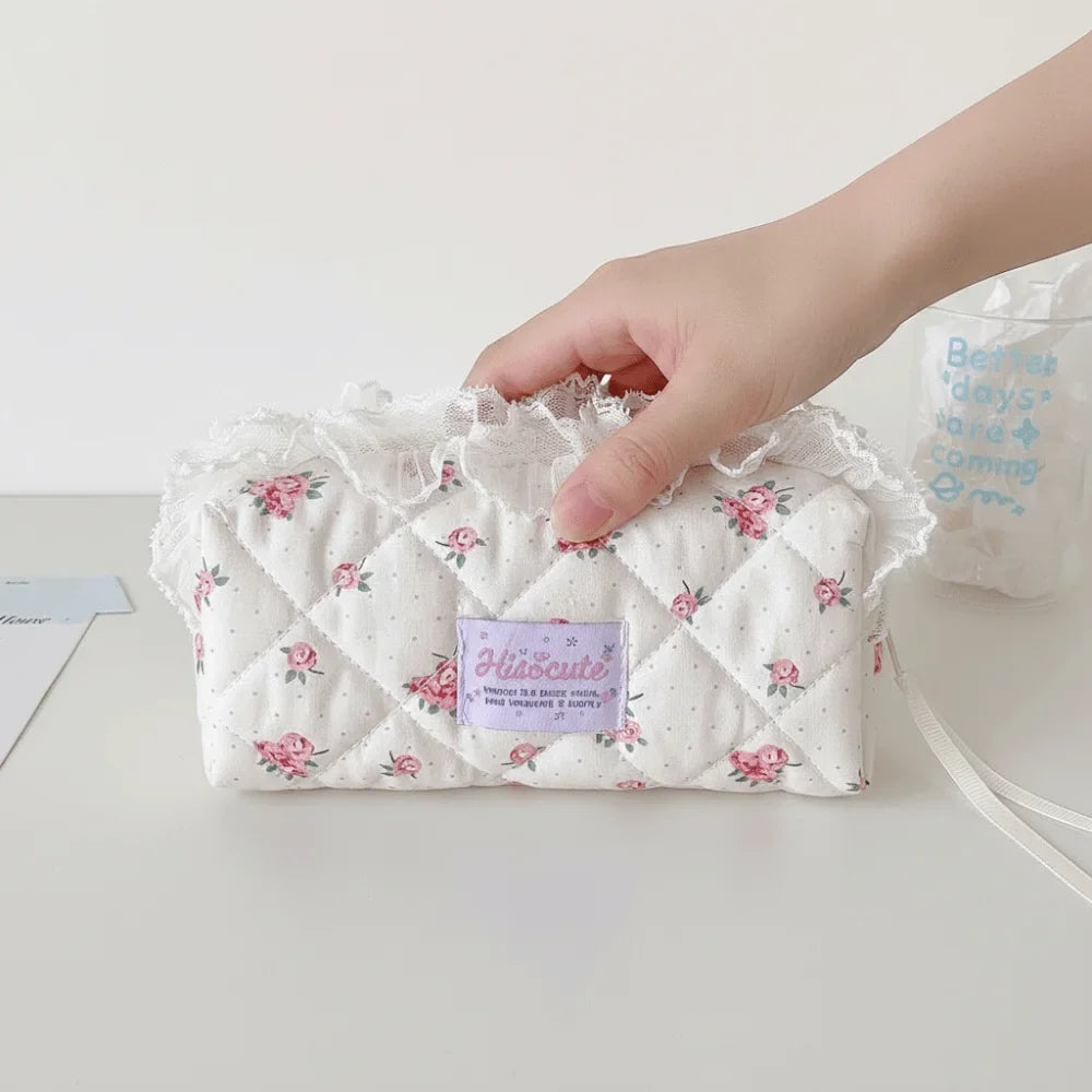 Quilted Ruffle Pencil Case: A hand holds the floral ruffle pencil case at its top edge 11