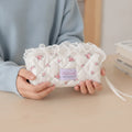 Quilted Ruffle Pencil Case: A person in a blue sweater holds a white quilted pencil case 2