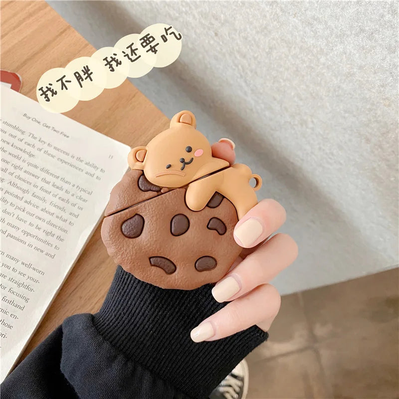 Teddy Bear Cookie AirPods Case: Teddy bear cookie earbud cover held beside an open book